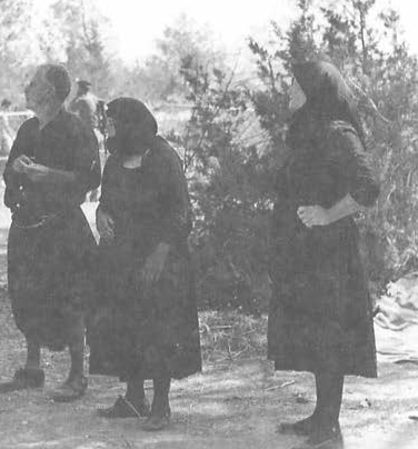 Elderly Cypriots in national dress with British soldiers in the background